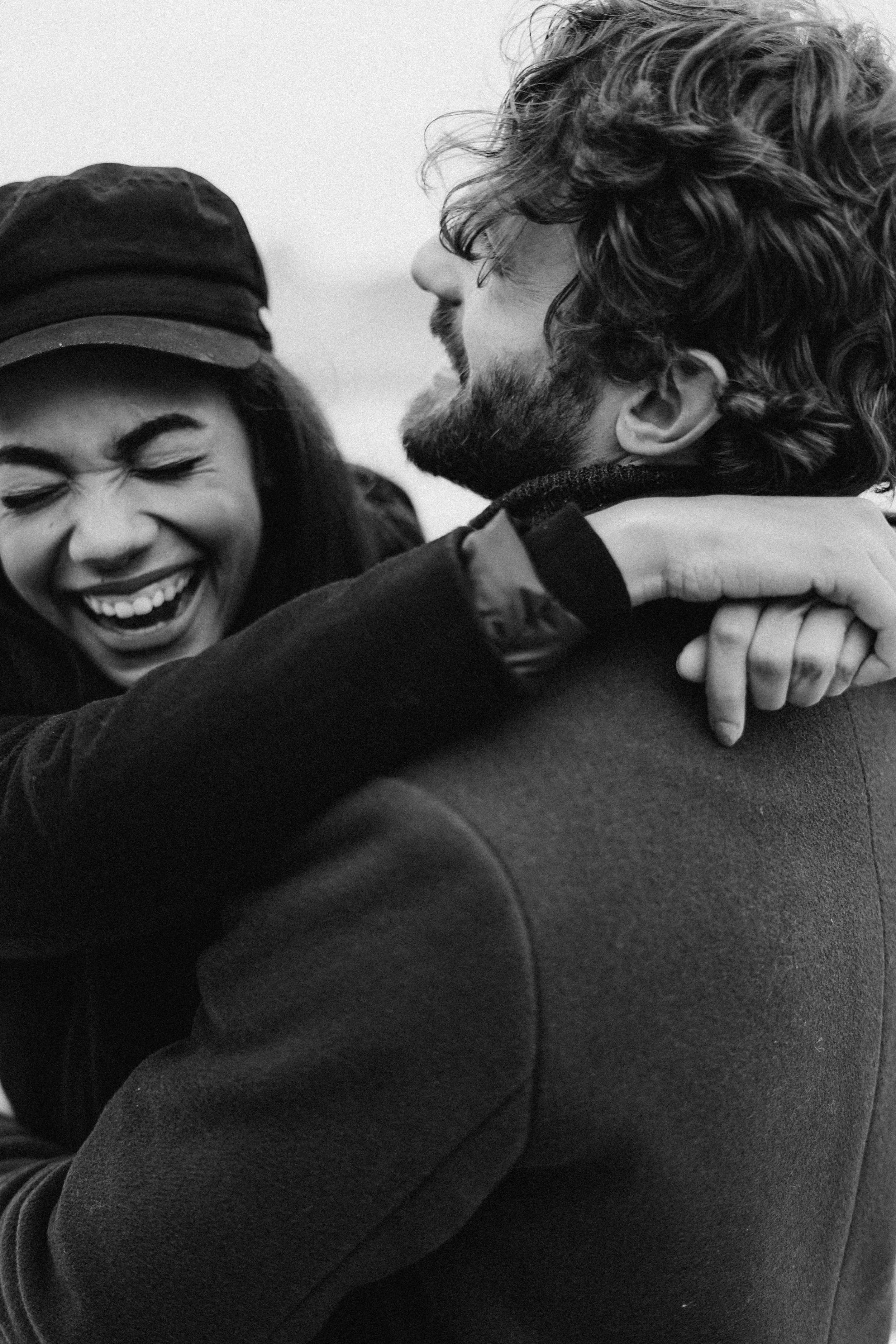A couple laughing, holding each other close.